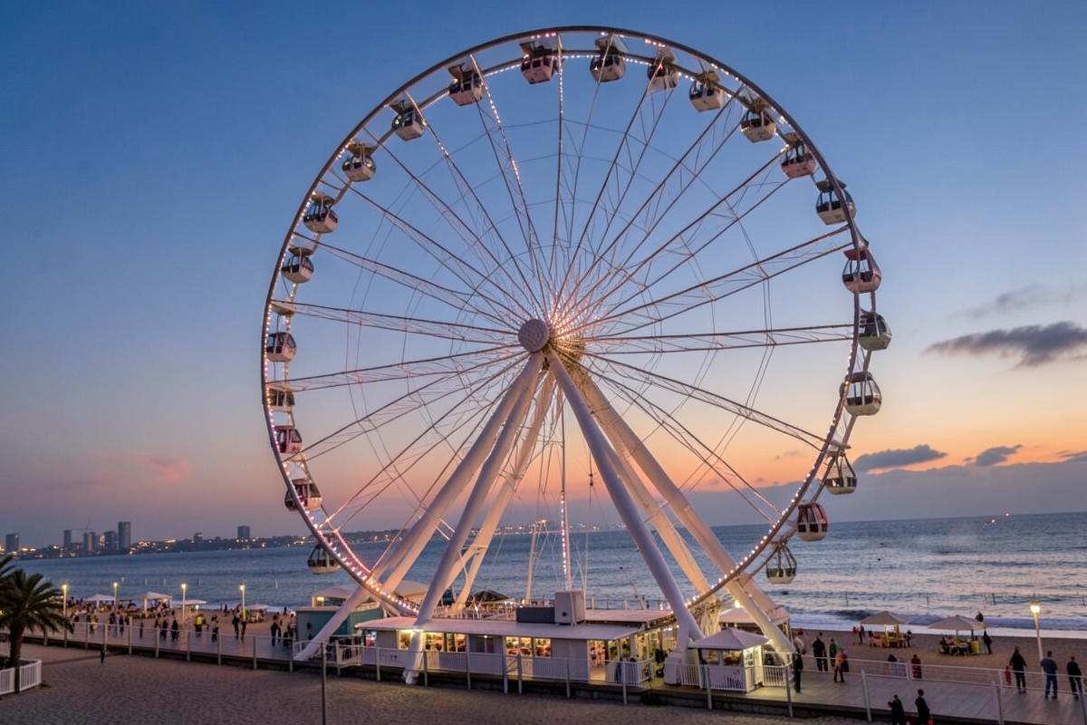 Roda gigante iluminada à beira-mar ao entardecer
